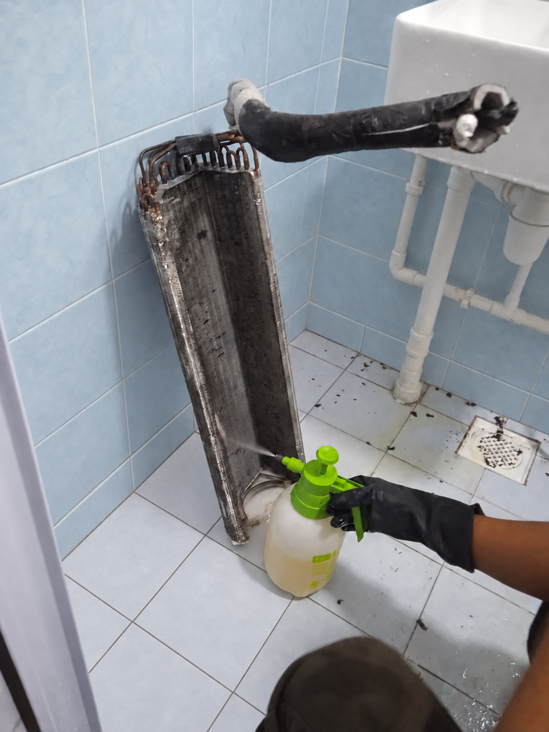 Technician chemical-washing an aircon coil